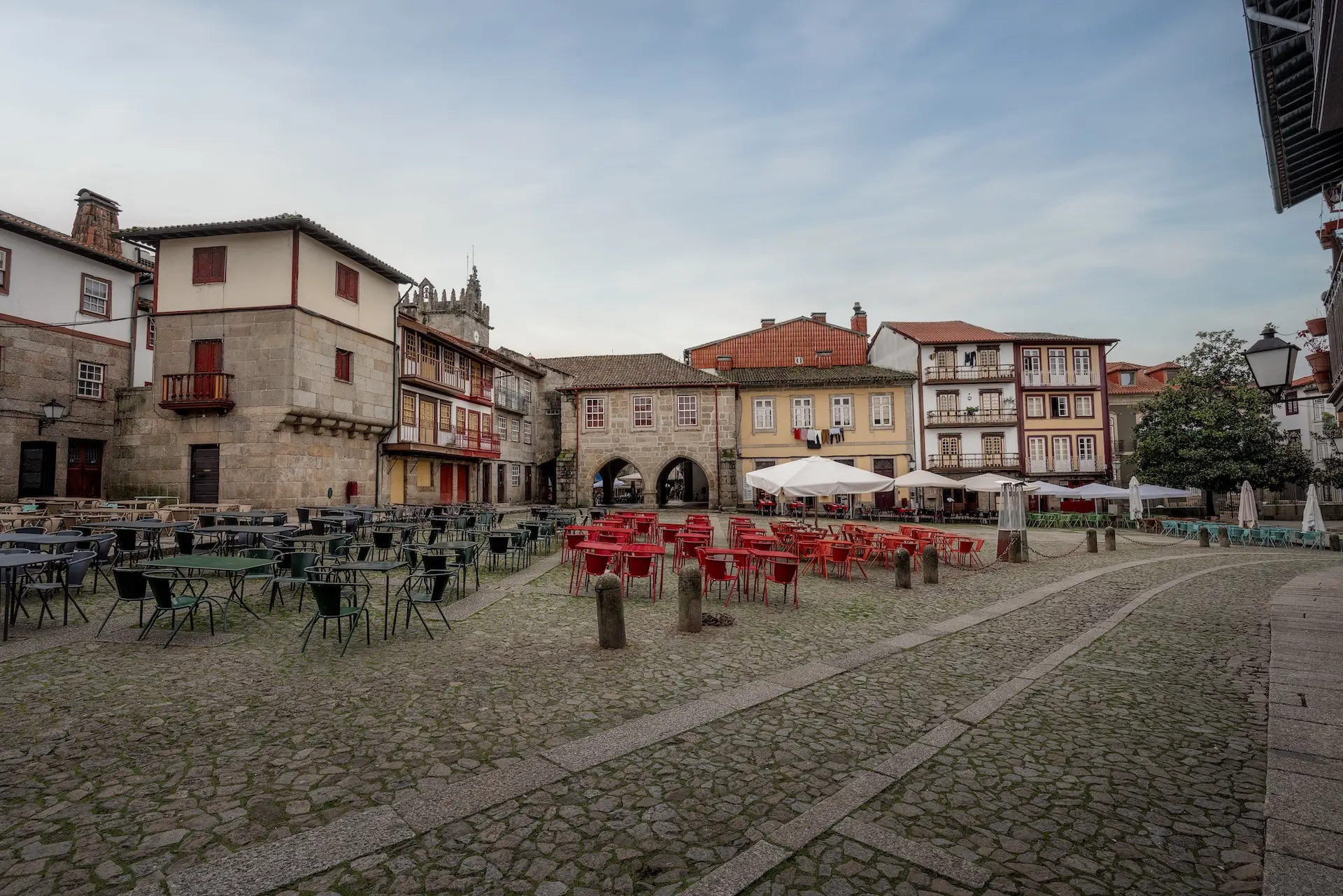 Fachada barroca do Santuário do Bom Jesus do Monte em Braga, com duas torres sineiras, escadaria monumental com estátuas e fonte, jardins floridos e vegetação exuberante ao fundo, em Portugal.